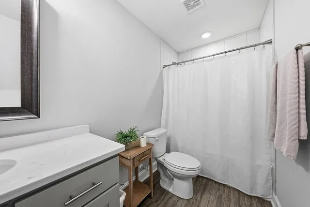 a bathroom with a sink a toilet a shower curtain and a mirror