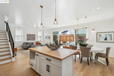 a view of a dining room and livingroom with furniture wooden floor a rug a flat screen tv a painting and a chandelier