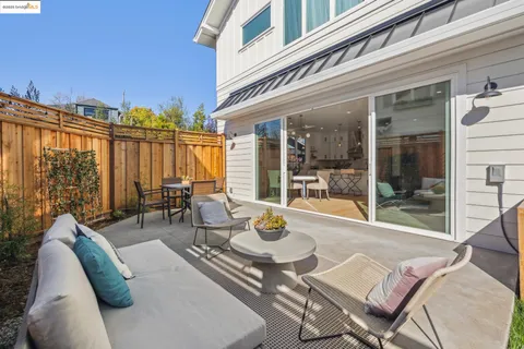 a view of a patio with couches table and chairs with wooden floor and fence
