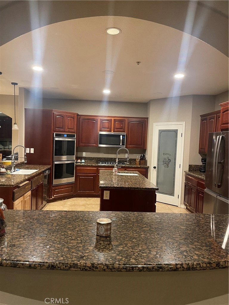 7677 Mono Road Phelan, CA 92371 - Photo 2 of 16 a large kitchen counter space with stainless steel appliances granite countertop a stove and cabinets