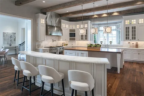 a kitchen with stainless steel appliances granite countertop a table chairs in it and wooden floors