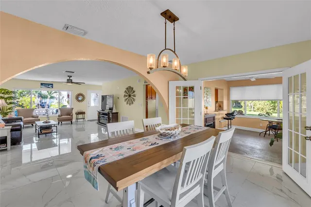 a dining room with wooden floor a chandelier a wooden table and chairs