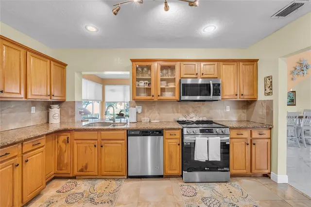 a kitchen with stainless steel appliances granite countertop a stove top oven a sink dishwasher and a microwave oven with cabinets