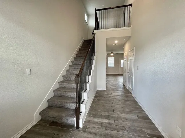a view of a hallway with wooden floor and staircase