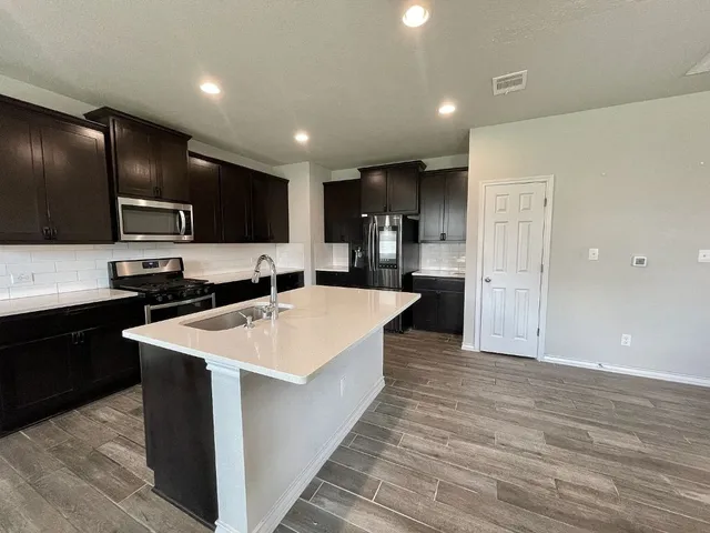 a large kitchen with stainless steel appliances kitchen island a large counter top and a refrigerator