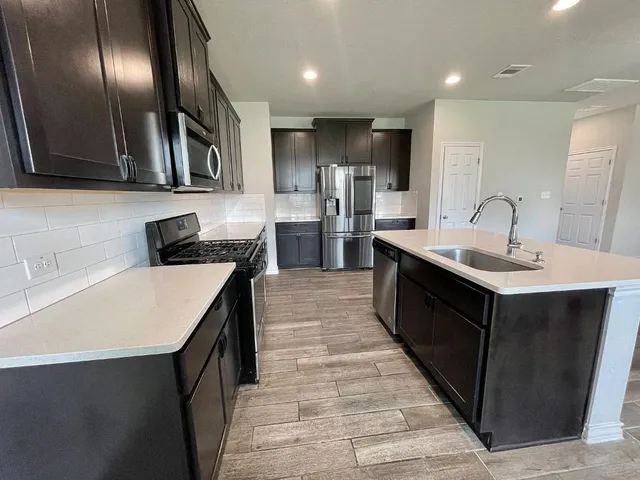 a kitchen with stainless steel appliances granite countertop a sink counter space cabinets and a wooden floor