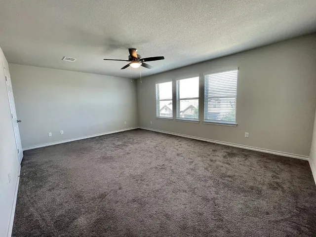 an empty room with windows and ceiling fan