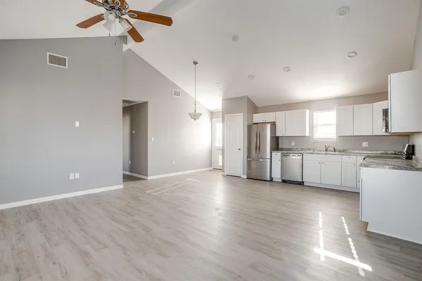 a view of a kitchen with a sink and dishwasher a refrigerator with wooden floor