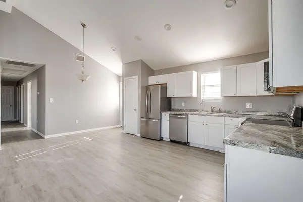 a kitchen with granite countertop a sink cabinets stainless steel appliances and a window