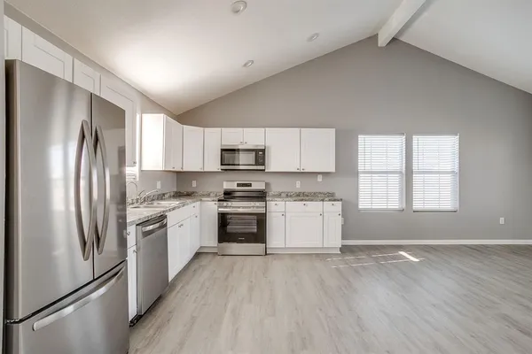 a kitchen with granite countertop stainless steel appliances a refrigerator sink and microwave