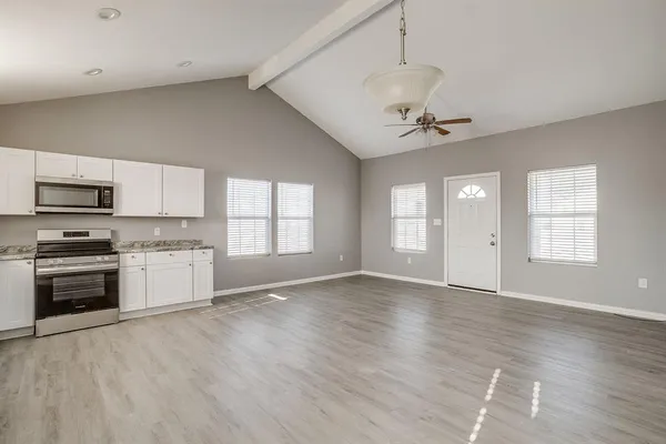 a view of an empty room with a kitchen and a window