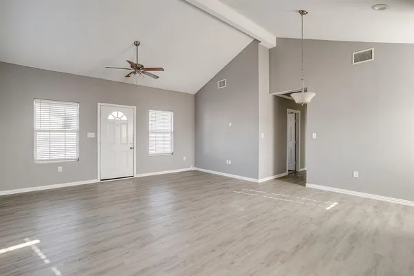 a view of an empty room with window and wooden floor