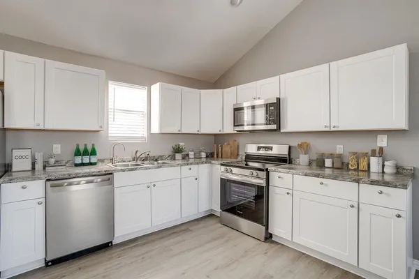 a kitchen with granite countertop white cabinets white stainless steel appliances with a sink and dishwasher