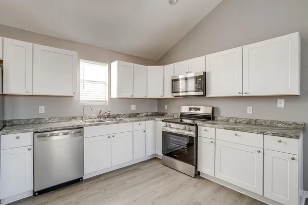 a kitchen with granite countertop white cabinets white stainless steel appliances with a sink and dishwasher