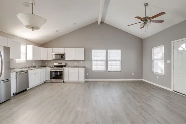 a large kitchen with cabinets wooden floor and stainless steel appliances