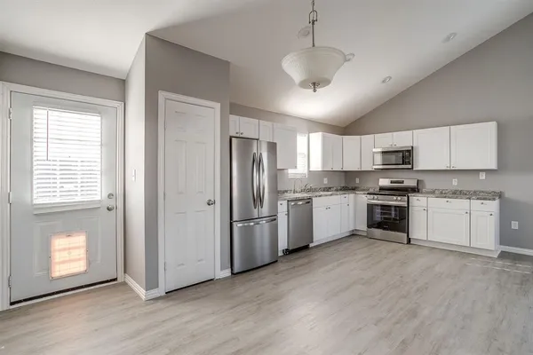 a large kitchen with stainless steel appliances granite countertop a stove a sink and a refrigerator