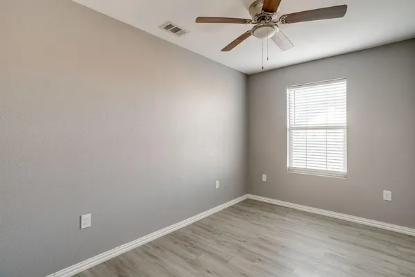 an empty room with a window and a fan