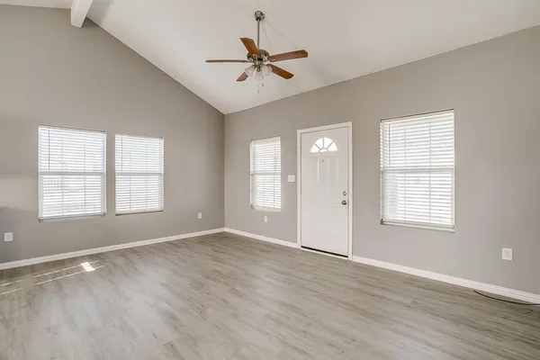 a view of an empty room with a window and wooden floor