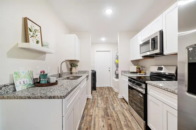 a kitchen with granite countertop a sink stove and microwave