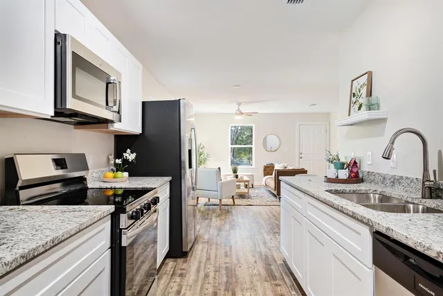 a kitchen with stainless steel appliances granite countertop a lot of counter space and wooden floors
