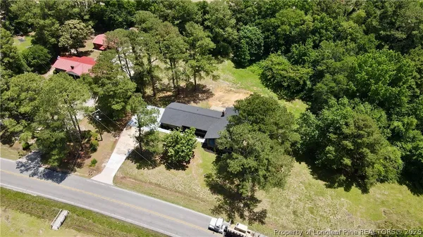 an aerial view of residential house with outdoor space and trees all around
