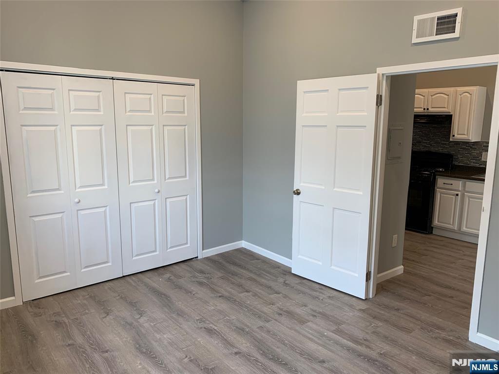 128 Locust Avenue, Unit A Wallington, NJ 07057 - Photo 6 of 13 an empty room with wooden floor & cabinet and a hallway