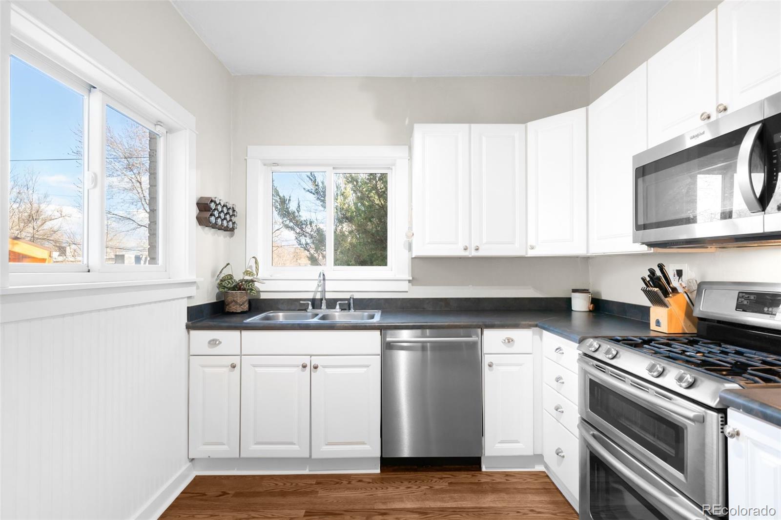 1032 Hooker Street Denver, CO 80204 - Photo 8 of 31 a kitchen with granite countertop a sink cabinets stainless steel appliances and a window
