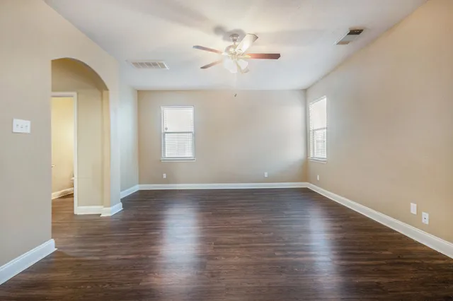 an empty room with wooden floor and windows