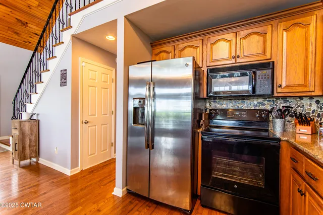 a kitchen with stainless steel appliances granite countertop a refrigerator a stove and a sink