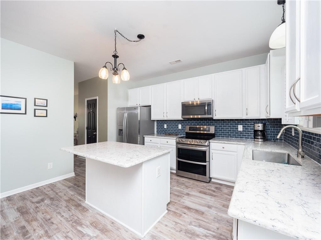 306 Green Pasture Road Mebane, NC 27302 - Photo 9 of 35 a kitchen with stainless steel appliances granite countertop a stove top oven a sink a refrigerator white cabinets and wooden floor