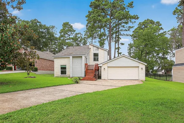 a view of a yard in front of a white house with plants and large tree