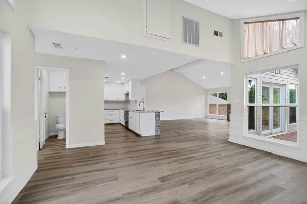 a view of an empty room with wooden floor and a window