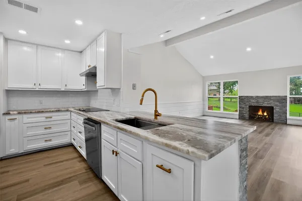 a kitchen with granite countertop a stove sink and cabinets