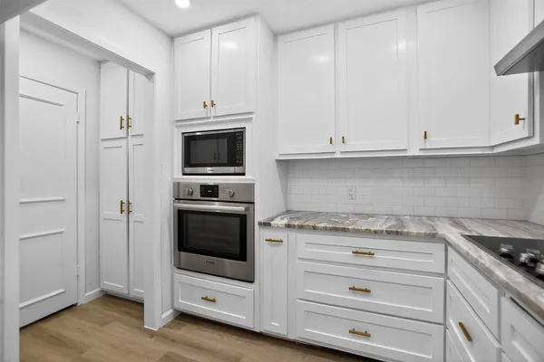 a kitchen with granite countertop white cabinets and stainless steel appliances