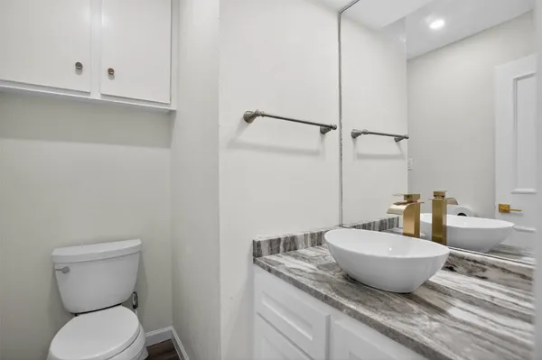 a bathroom with a granite countertop toilet and sink