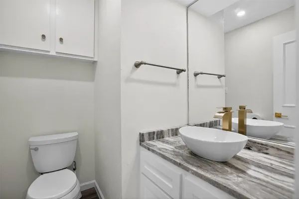 a bathroom with a granite countertop toilet and sink