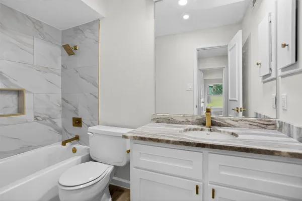 a bathroom with a granite countertop sink toilet and shower