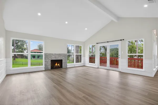 a view of an empty room with wooden floor and a fireplace
