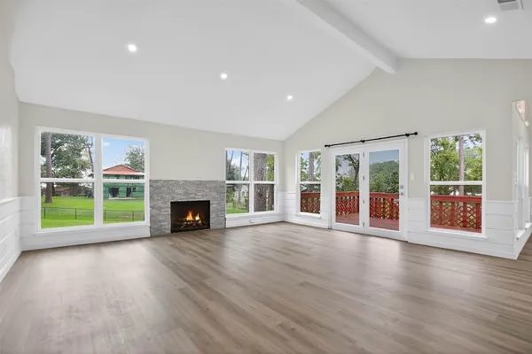 a view of an empty room with wooden floor and a fireplace
