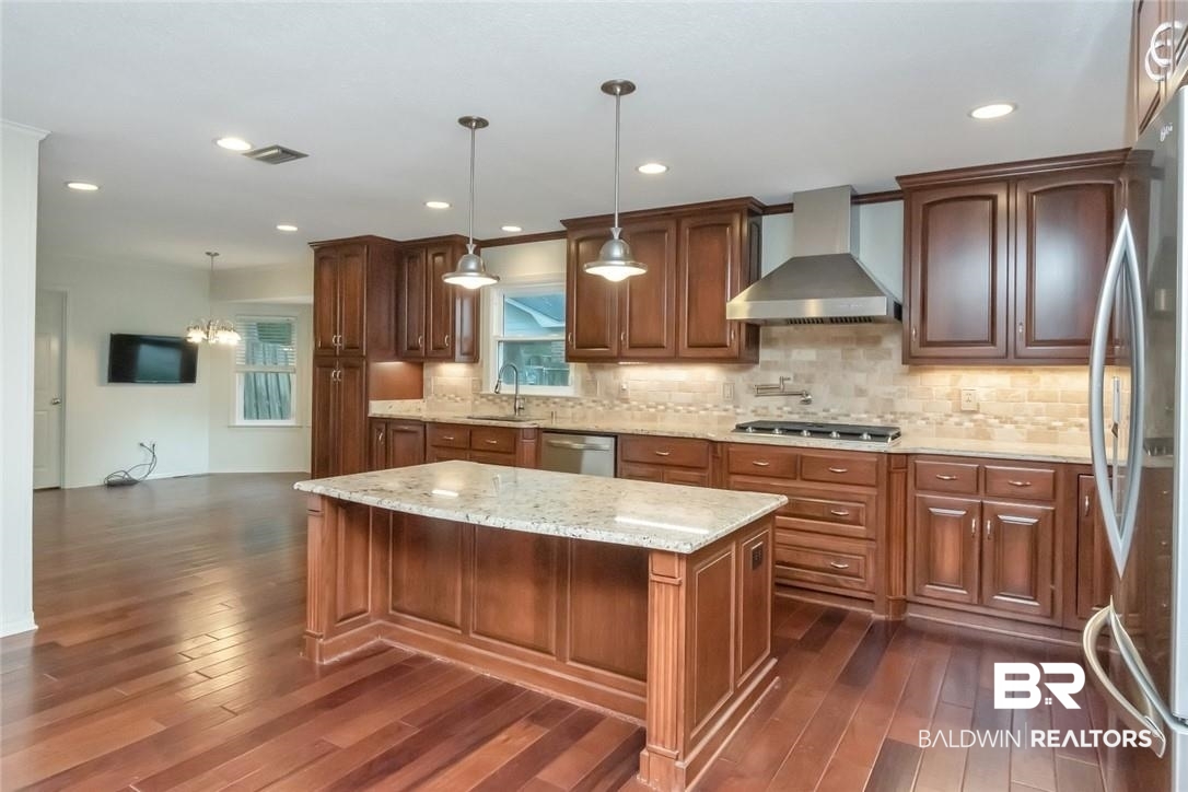 6109 Timberly Road North Mobile, AL 36609 - Photo 5 of 26 Kitchen featuring hanging light fixtures, dark hardwood / wood-style floors, wall chimney range hood, and a kitchen island