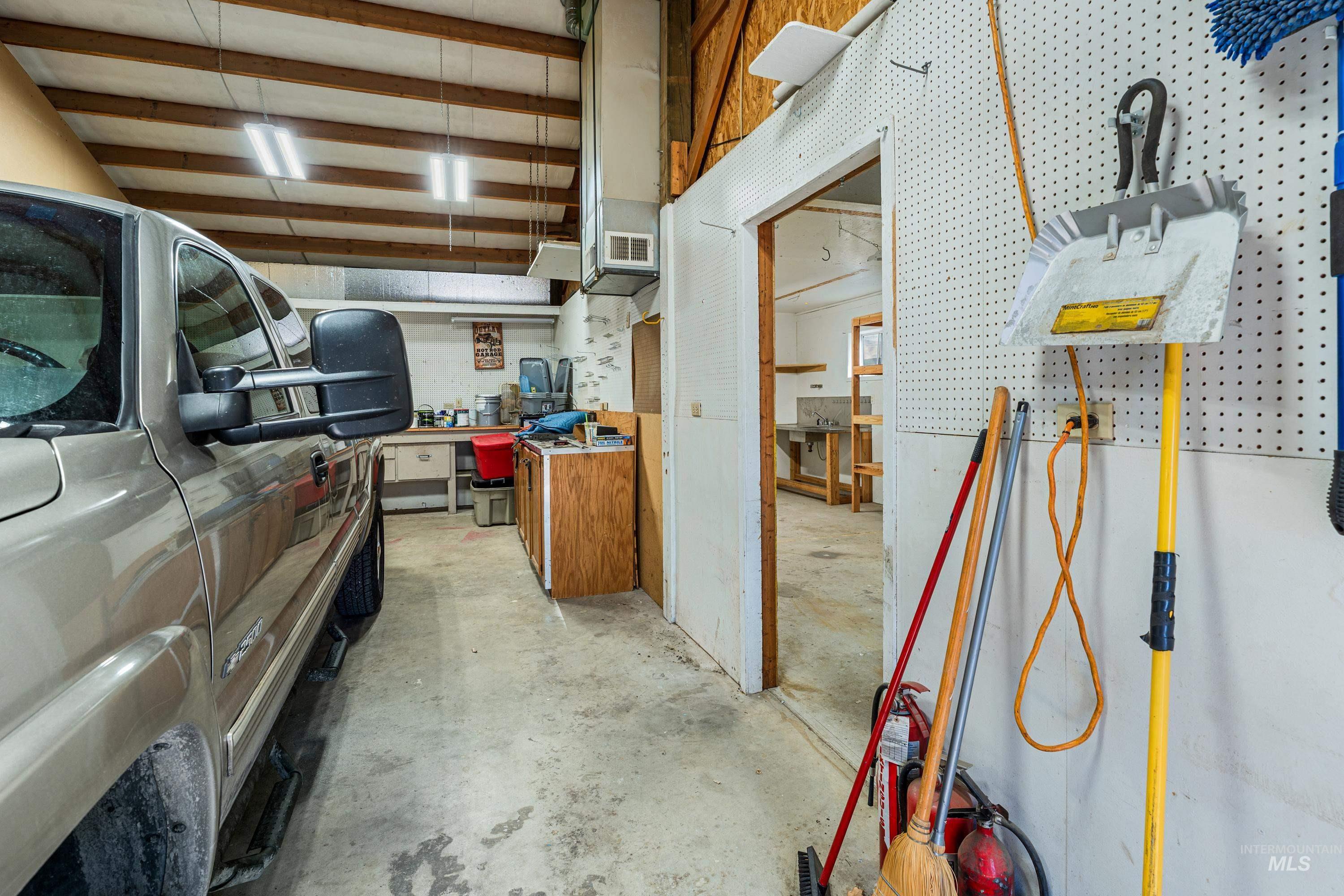 1266 Maple Street Clarkston, WA 99403 - Photo 35 of 44 Concrete flooring, exposed wood beam ceiling, fluorescent lighting, and a utility room with a workbench and sink