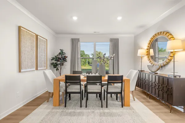 a living room kitchen with stainless steel appliances granite countertop a couch and a dining table with wooden floor