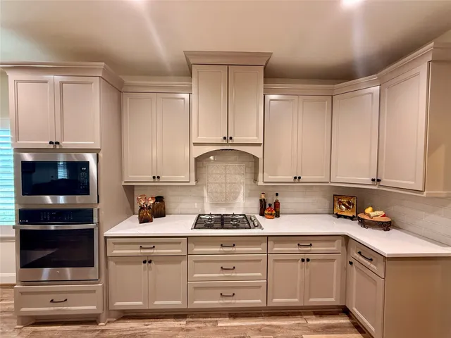 a kitchen with granite countertop white cabinets and stainless steel appliances