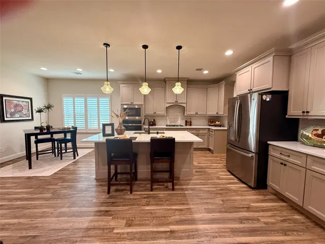 a kitchen with stainless steel appliances granite countertop a refrigerator a stove a sink a oven with a dining table and chairs