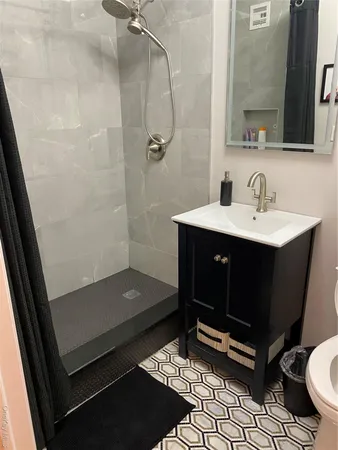 a bathroom with a sink a toilet a mirror and shower