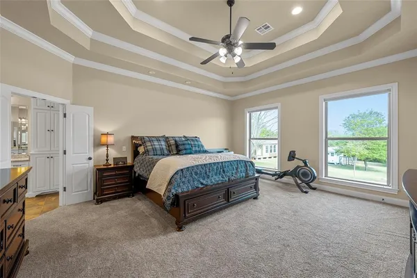 a spacious bedroom with a bed a dresser and a large window