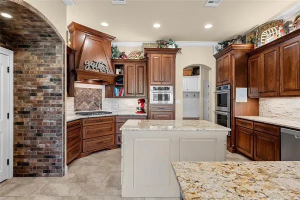 a kitchen with stainless steel appliances kitchen island granite countertop a sink and a refrigerator