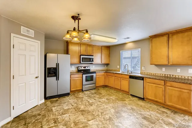 a large kitchen with stainless steel appliances granite countertop a stove refrigerator and a sink
