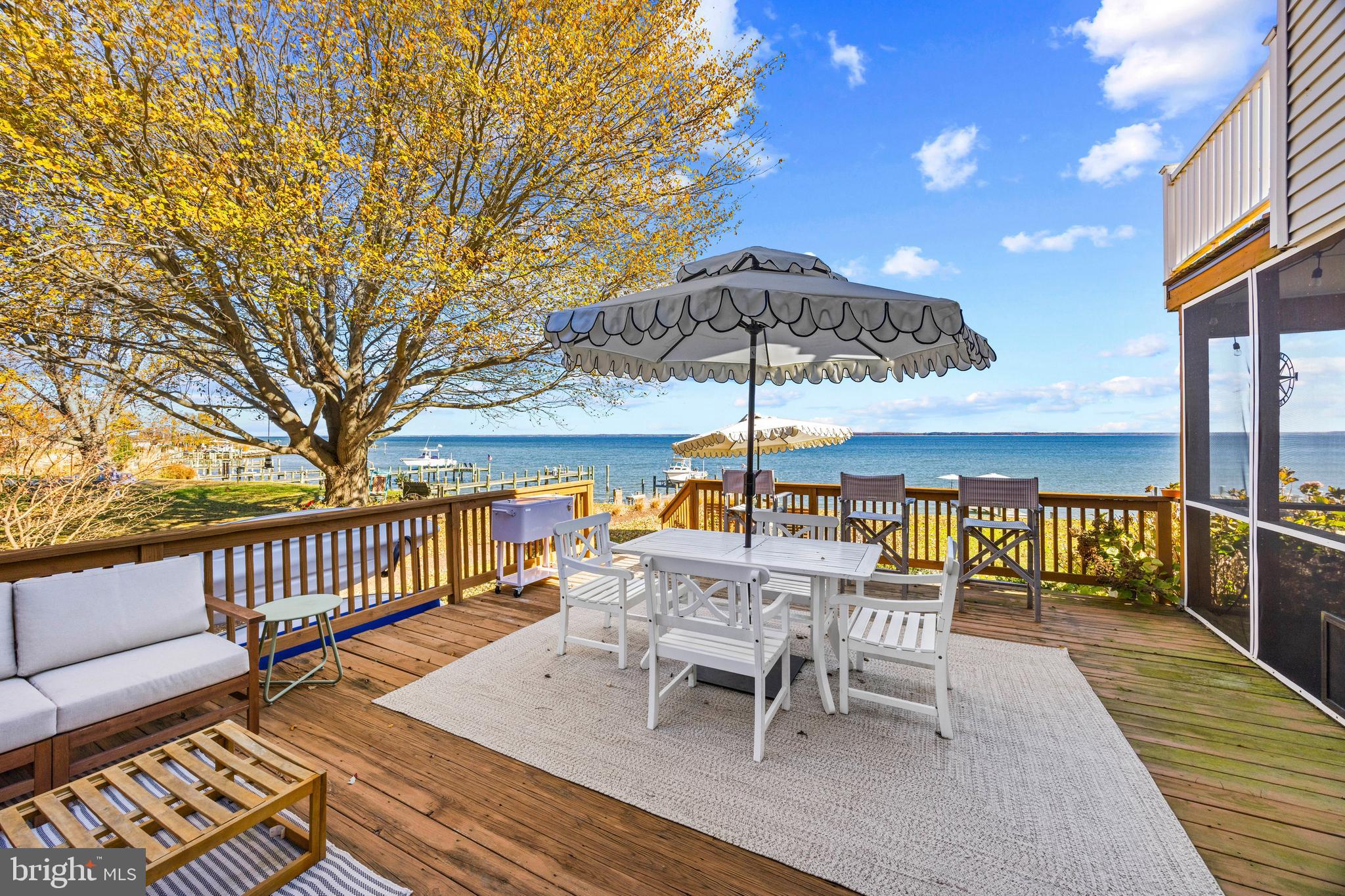 806 Monroe Manor Road Stevensville, MD 21619 - Photo 20 of 41 a view of a roof deck with table and chairs under an umbrella with wooden floor