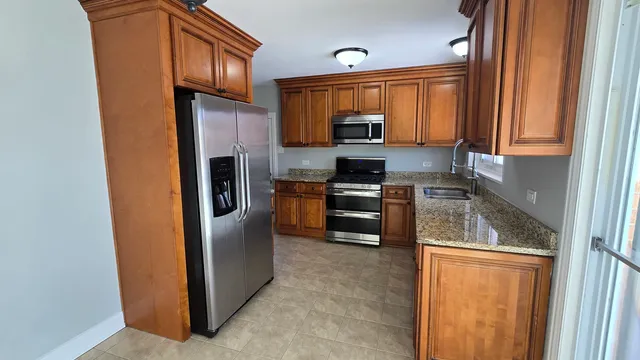 a kitchen with stainless steel appliances granite countertop a refrigerator stove and sink
